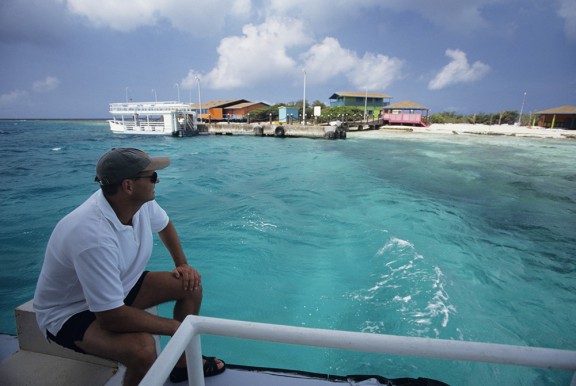 Man sitting on boat looking out over beach in Aruba